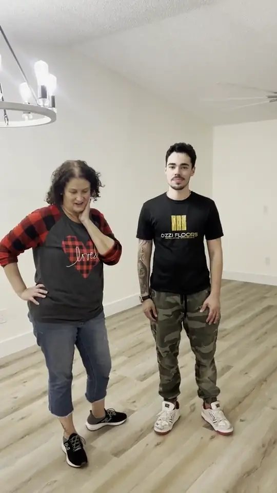 An Ozzifloors team member standing with a customer on her newly installed grey plank floor